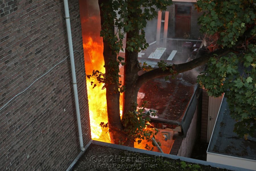 Hoge vlammen bij brand achter telefoonwinkel aan de Lange Herenstraat