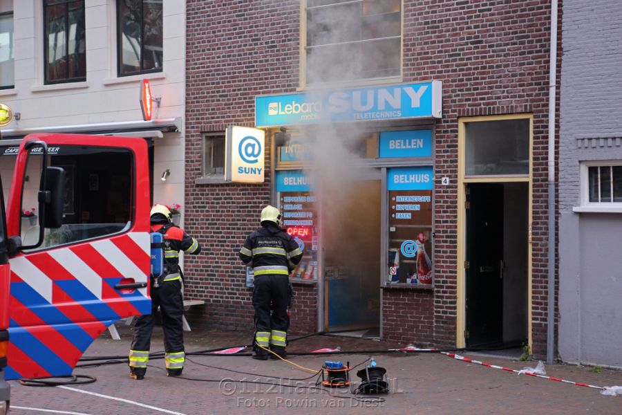 Hoge vlammen bij brand achter telefoonwinkel aan de Lange Herenstraat